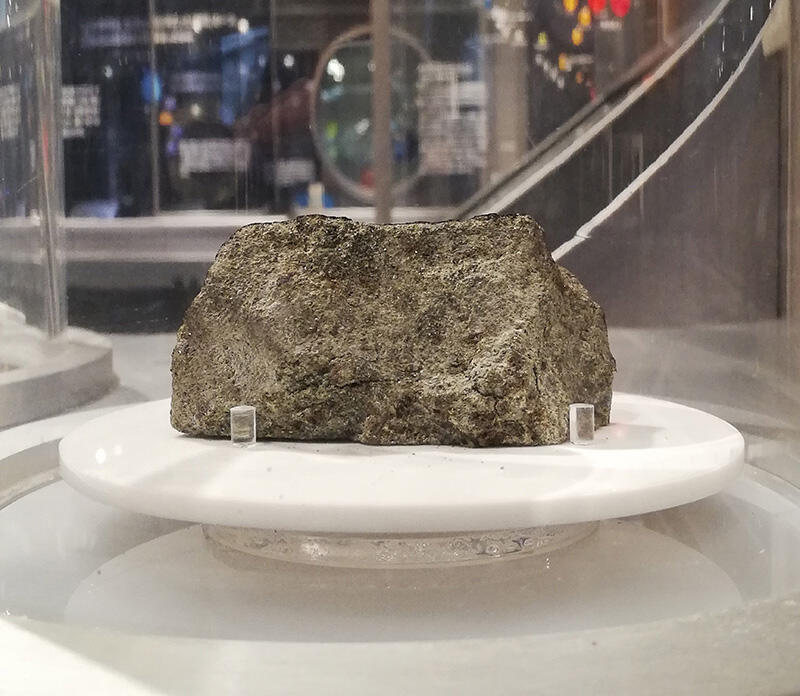 The Nakhla meteorite on exhibition on floor B3 of the Science Museum's Global Gallery. It is six centimeters-long and composed mainly of a greenish mineral called augite.
