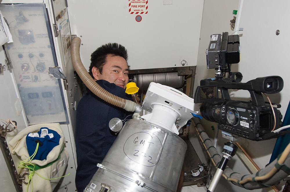 HOSHIDE repairing a toilet in the ISS, replacing the tank together with hose and pump connections (Photo taken on October 2, 2012 (JST))