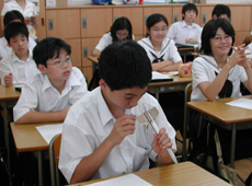 A student holding a model of the first Japanese rocket, known as a pencil rocket.