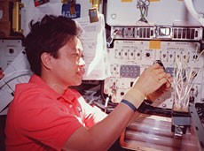 Astronaut Chiaki Mukai performing an experiment on the Space Shuttle STS-95 (courtesy of NASA)