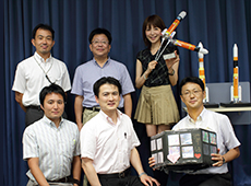 Project manager Takeshi Fujita, back row, center. H-IIA Upgrade Project team and Ms. Saeko Ishida at the recording of a JAXA program reporting the latest news on aerospace.